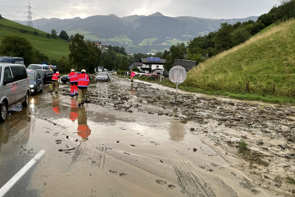 Einsatzkräfte befreien die Rauriser Landesstraße im Salzburger Land von Schlamm, nachdem starke Regenfälle einen Erdrutsch ausgelöst haben.