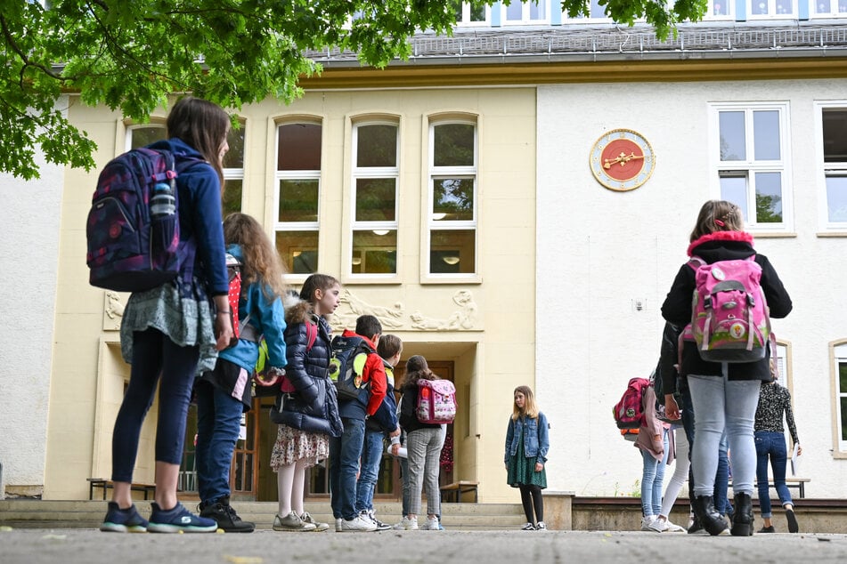 Schülerinnen und Schüler einer vierten Klasse stehen mit Abstand auf einem Schulhof. (Archivbild)