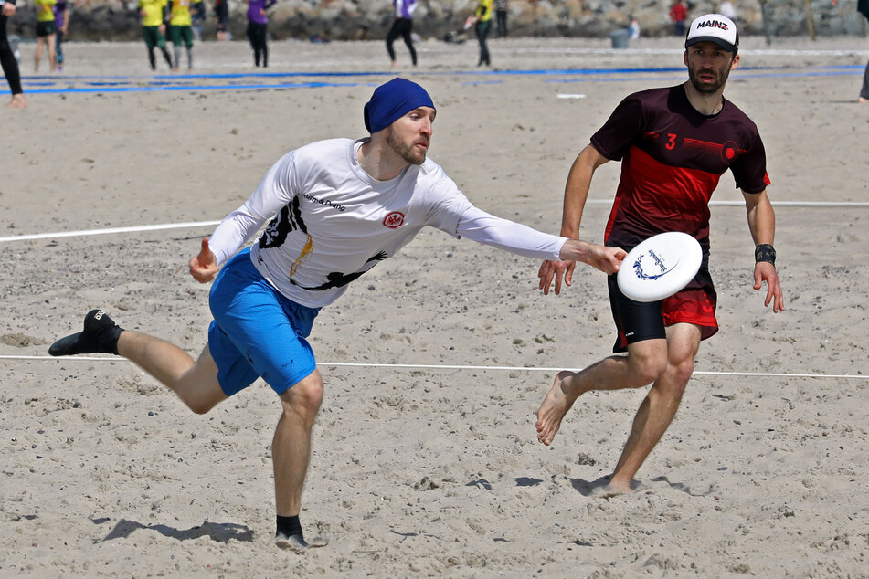 Bei der Deutschen Meisterschaft im Strand-Frisbee sind die Mannschaften von Eintracht Frankfurt (weiß) und Mainzelrenner (rot) am Ostseestrand in Aktion.