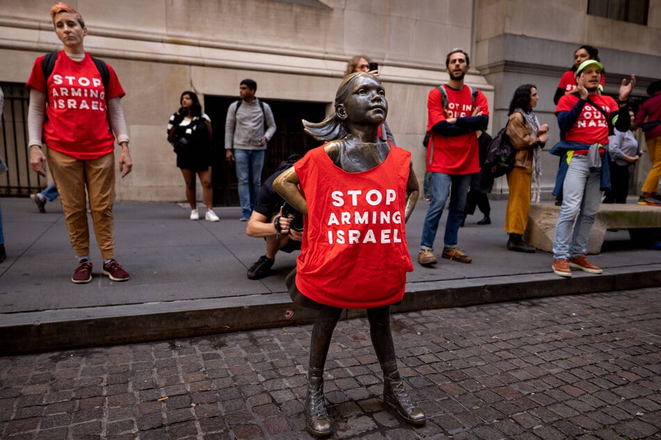 The Fearless Girl statue wears a t-shirt that says "Stop Arming Israel" during a pro-Palestine sit-in outside the New York Stock Exchange.