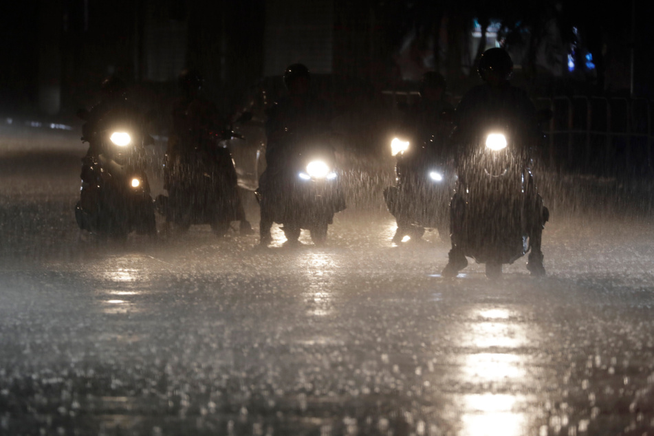 Mopedfahrer warten an einer Kreuzung bei starkem Regen in Taipeh.