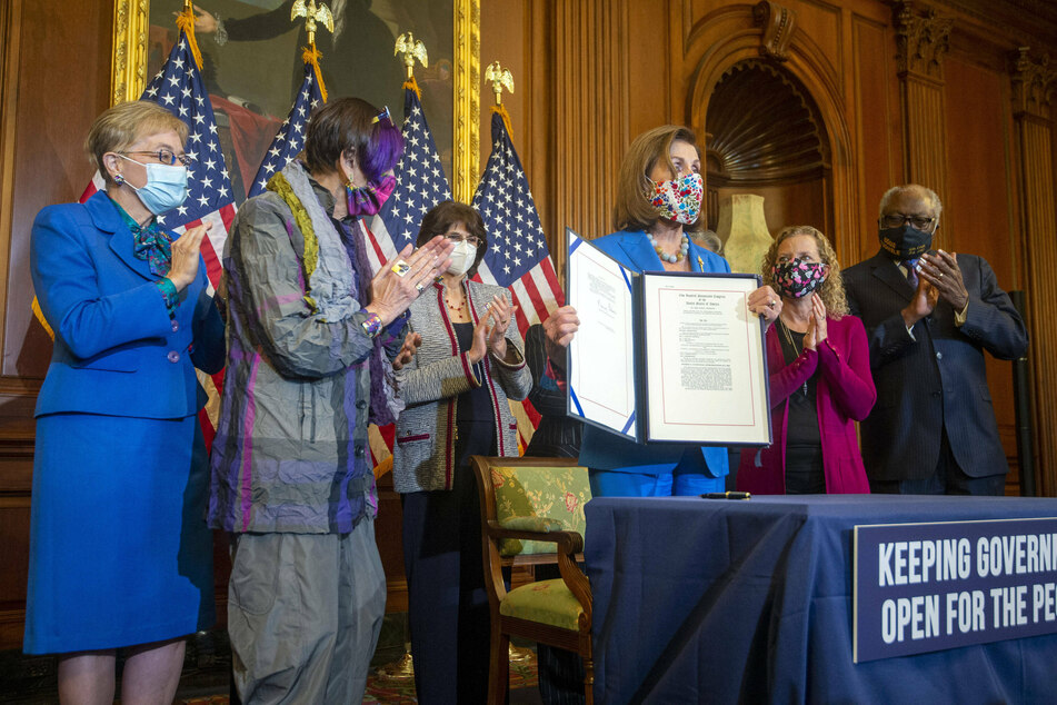 Speaker of the House Nancy Pelosi holds up a House continuing resolution to keep funding the government.