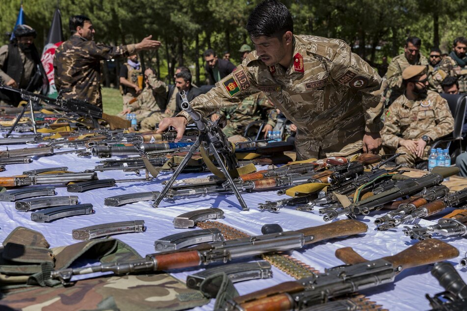 An Afghan security force member inspects the weapons handed over by Taliban militants in Herat, Afghanistan.