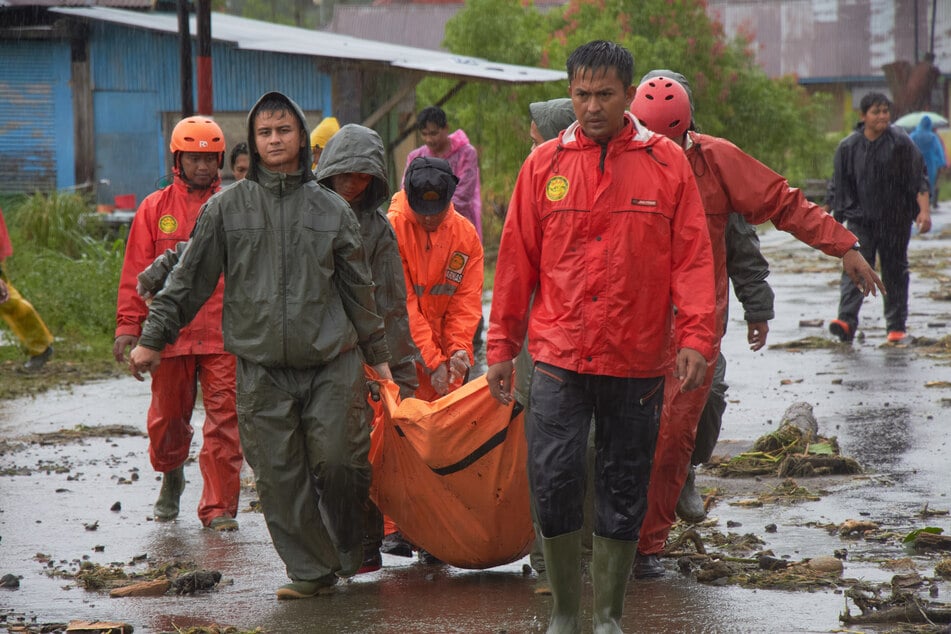 Rettungskräfte tragen die Leiche eines Opfers in einem überschwemmten Dorf in Malalak, Westsumatra.