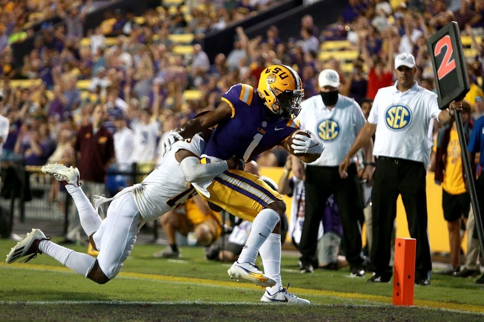 Kayshon Boutte of the LSU Tigers scores a touchdown over Donte Kent of the Central Michigan Chippewas during the second quarter at Tiger Stadium .