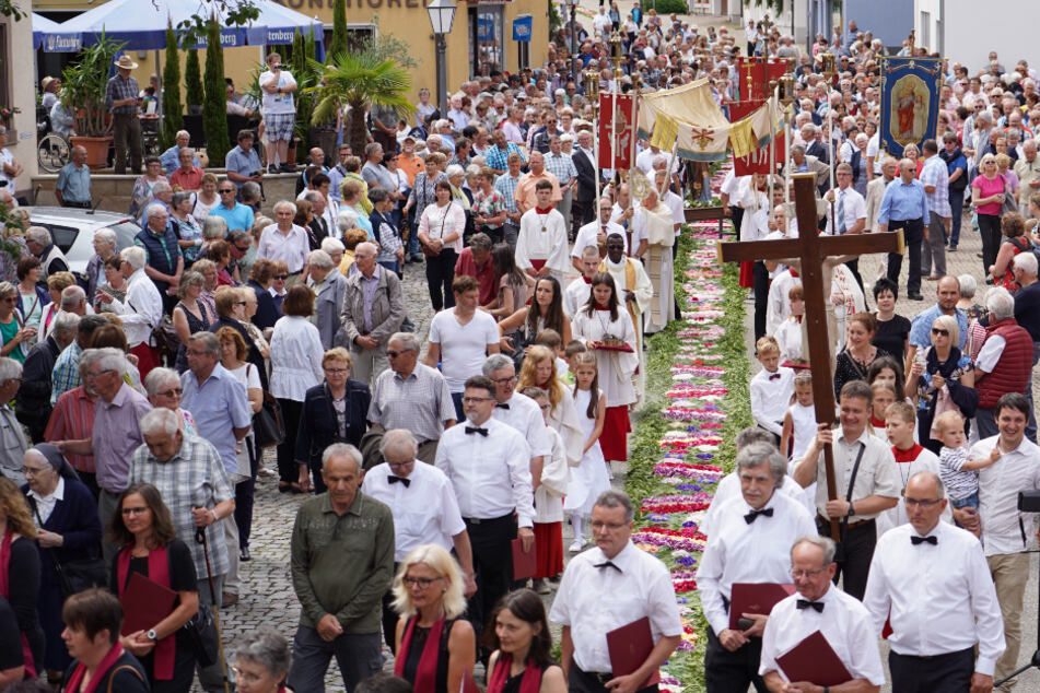 Mühlenbach 2019: Gläubige gehen während der Fronleichnams-Prozession an einem Blumenteppich entlang.