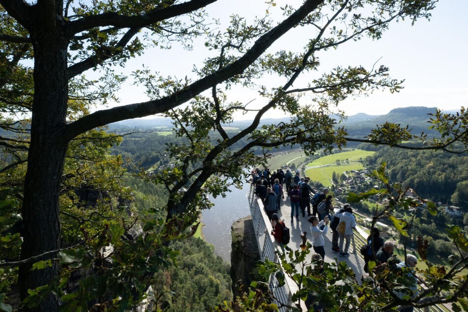 Touristen stehen im Nationalpark Sächsische Schweiz auf einer Aussichtsplattform auf dem Basteifelsen.