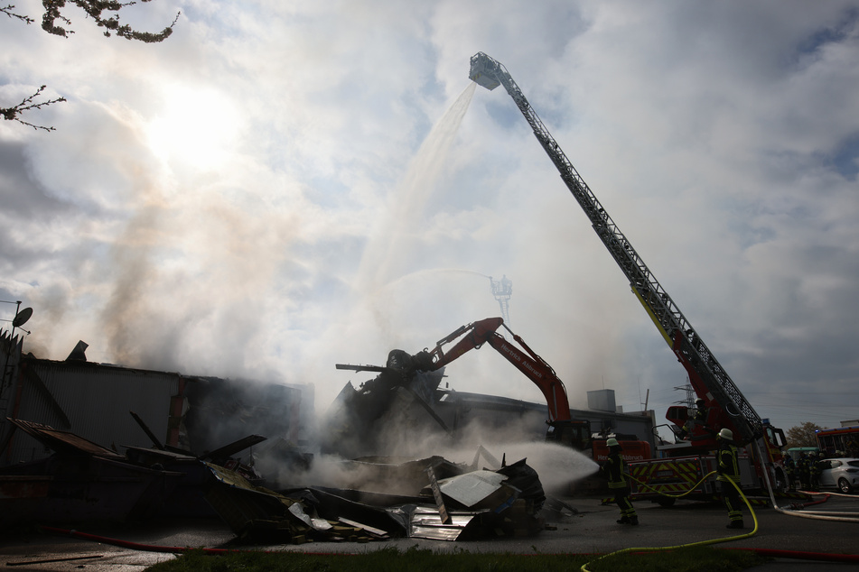 Mit schwerem Gerät arbeitet sich die Feuerwehr zu Glutnestern vor nach einem Brand in einem Club.