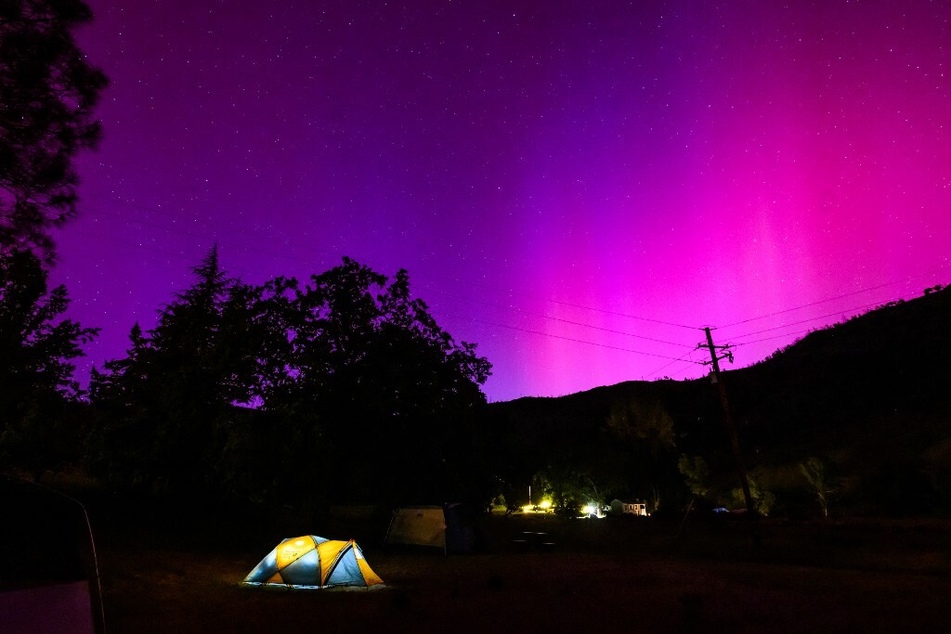 Aurora borealis illuminate the night sky over a camper's tent north of San Francisco in Middletown, California.