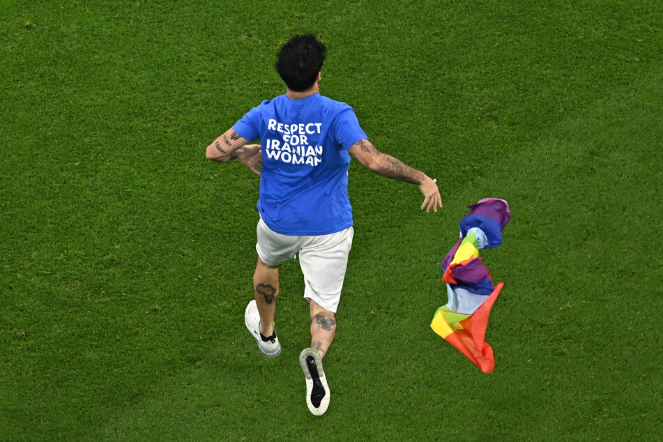 Der Flitzer trug ein T-Shirt mit der Aufschrift "Respect for Iranian Woman" und ließ eine Regenbogenflagge auf dem Spielfeld fallen.