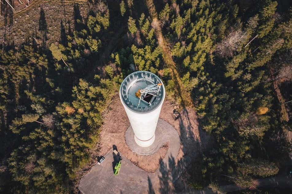 Eine Drohnenaufnahme einer Windkraftanlage inmitten eines dichten Waldes.