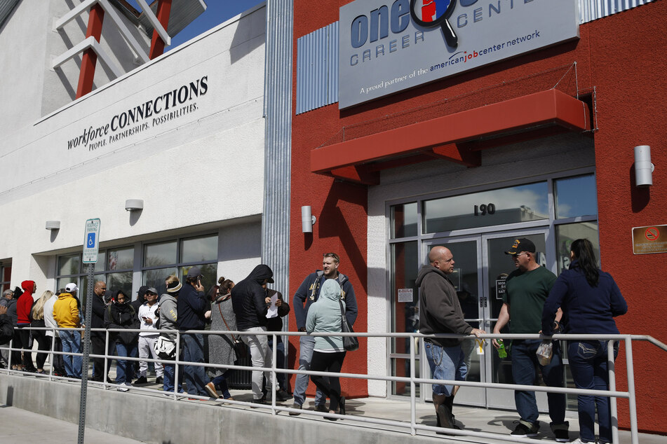 Menschen stehen in einer Schlange vor einem Jobcenter, um Arbeitslosenhilfe zu beantragen.