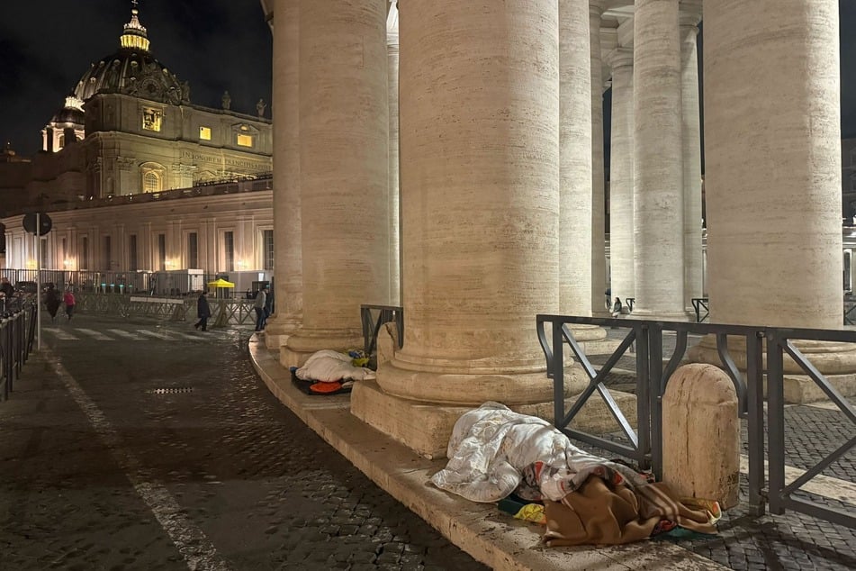 Unter den Kolonnaden am Petersplatz liegen Obdachlose in Schlafsäcken, um dort die Nacht zu verbringen.
