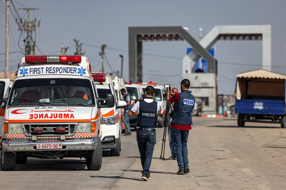 Journalisten halten den Moment fest, wie Krankenwagen des palästinensischen Gesundheitsministeriums das Tor zum Grenzübergang Rafah im südlichen Gazastreifen passieren, bevor sie nach Ägypten weiterreisen.