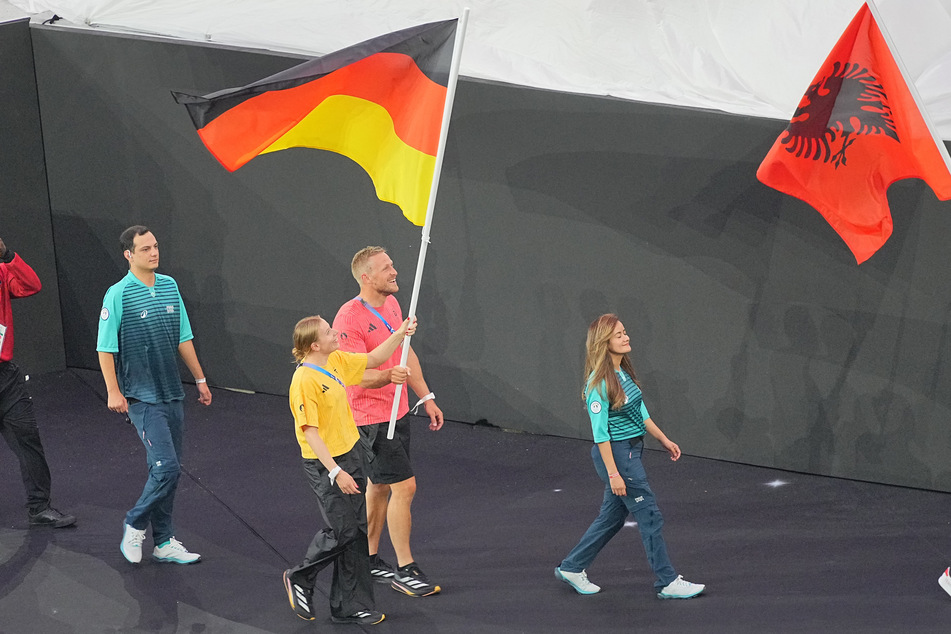 Laura Lindemann und Max Rendschmidt tragen die deutsche Fahne bei der Olympia-Abschlussfeier ins Stade de France.