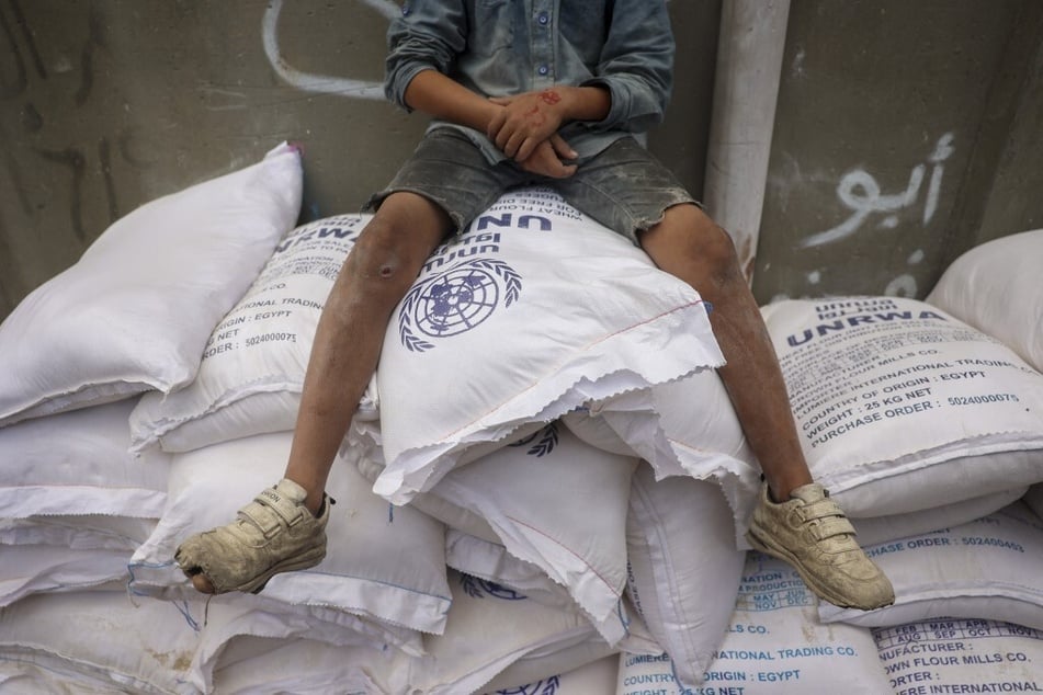 A Palestinian child sits on top of sacks of flour at an UNRWA aid distribution center in Deir el-Balah in the central Gaza Strip.