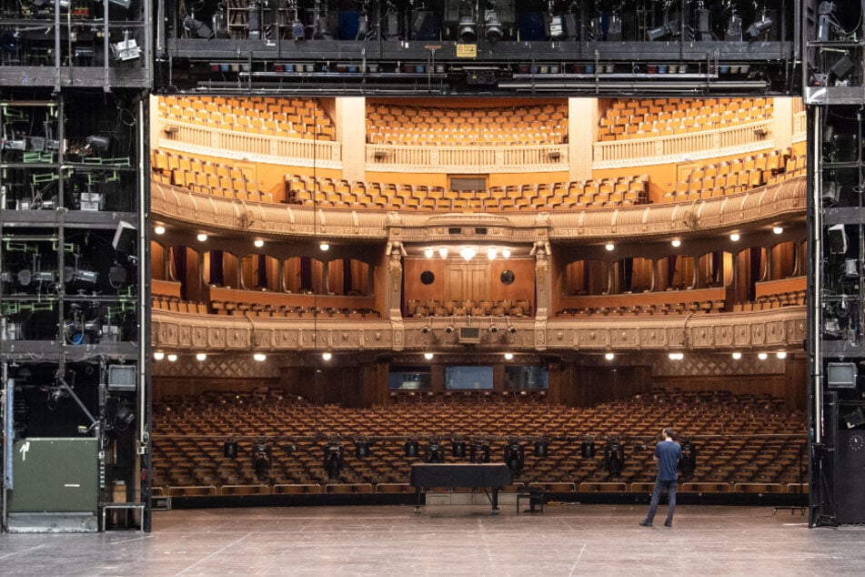 Ein Mitarbeiter der Staatstheater Stuttgart steht auf der Bühne des Opernhauses der Staatstheater Stuttgart, im Hintergrund ist der Zuschauerraum zu sehen.