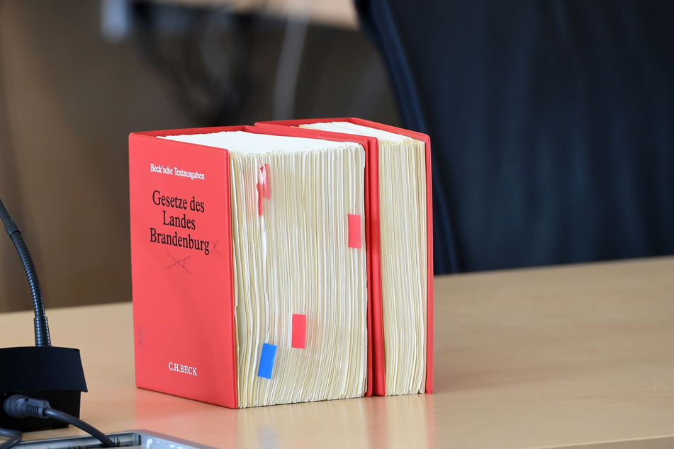 Ein Buch mit der Aufschrift "Gesetze des Landes Brandenburg" steht in einem Saal des Verfassungsgerichtes auf einem Tisch. (Archivbild)