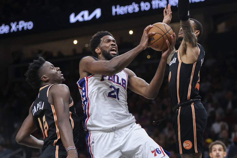 Philadelphia 76ers center Joel Embiid shoots past Atlanta Hawks center Clint Capela and forward John Collins in the second quarter at State Farm Arena.