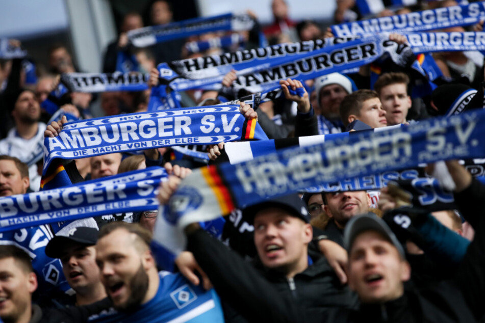 Fans des Hamburger SV halten ihre Fanschals und singen vor dem Anpfiff.