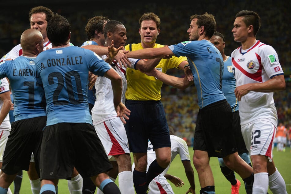 Felix Brych (M.) durfte unter anderem auch bei der WM 2014 pfeifen und hatte im Spiel zwischen Uruguay und Costa Rica alle Hände voll zu tun. (Archivfoto)