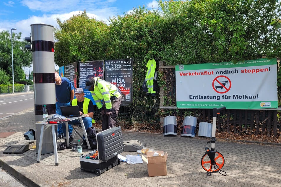 Auf einem Banner wird gefordert, dass die Stadt den Ortsteil entlastet. Der Blitzer soll helfen. Techniker programmierten ihn am Donnerstag.