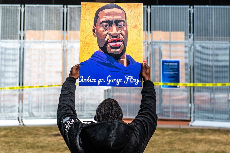 A man holds up a picture showing a portrait of George Floyd during a demonstration against police violence.