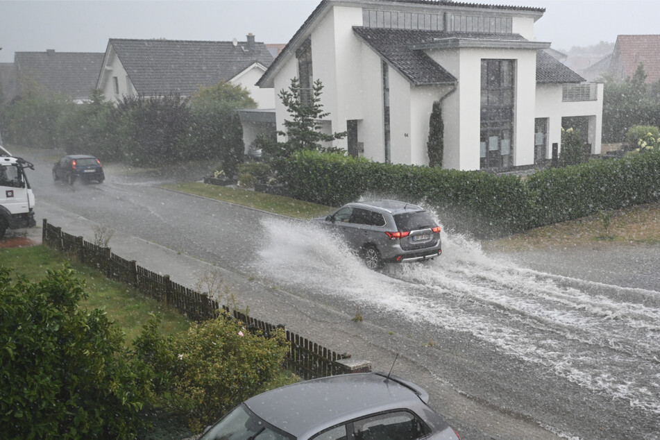 Ein Auto fährt auf einer überfluteten Straße.