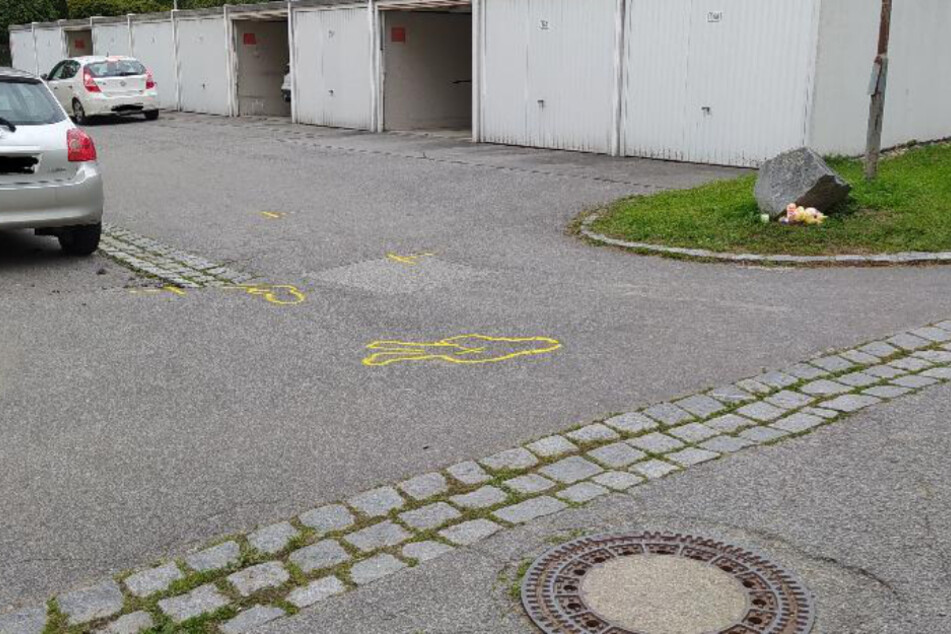 Markierungen am Boden zeugen von dem tragischen Unglück in Deggendorf. Rechts sind zur Trauerbekundung Gegenstände niedergelegt.