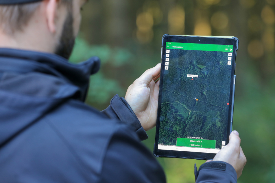 Forstunternehmer Michael Widiner hält ein Tablet mit seiner selbstentwickelten App "MW-ForstApp" in der Hand.