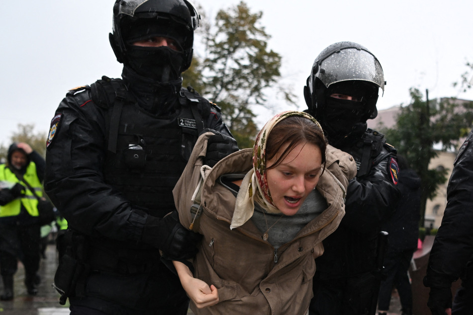 Ein junge Frau wird von Polizisten während eine Anti-Kriegs-Demo in Moskau abgeführt.