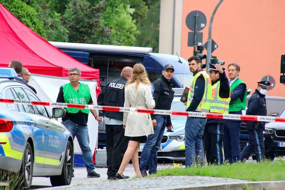 Polizisten steht am Tatort, an dem zuvor ein Mann auf der Straße umgebracht wurde.