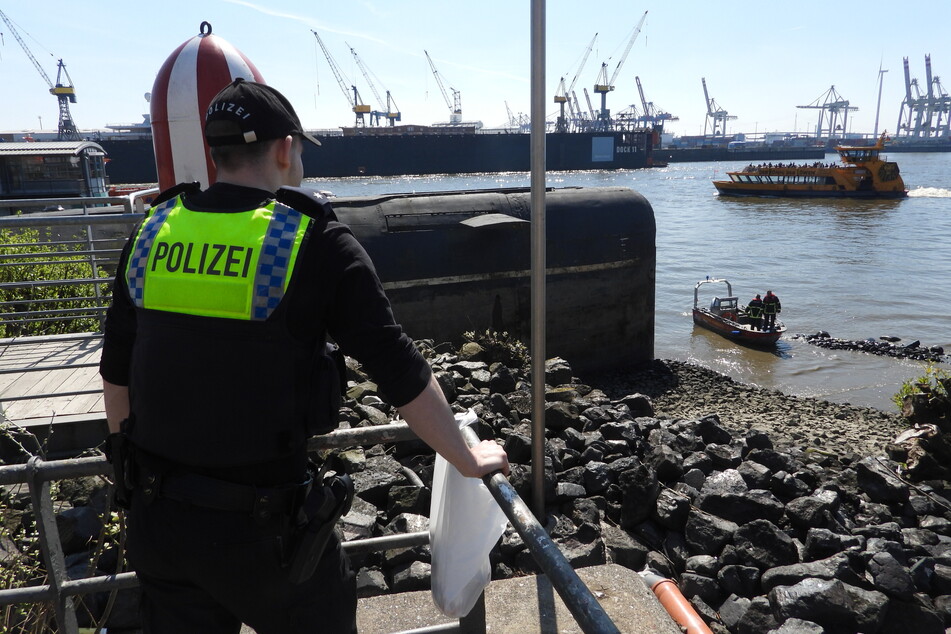 Ein Polizist blickt auf den Fundort am Ufer der Elbe.