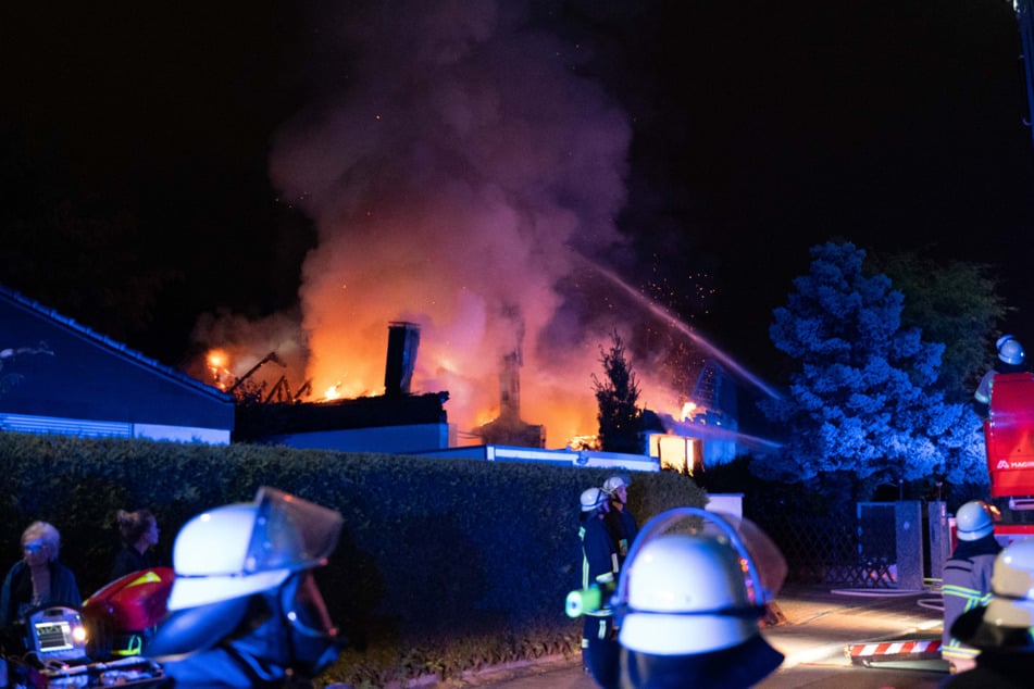Feuerwehrleute stehen vor dem brennenden Gebäude in Fürth.