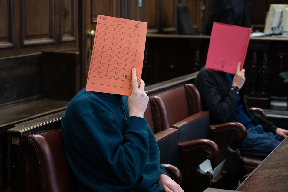 Zwei der drei Angeklagten sitzen im Landgericht im Saal.