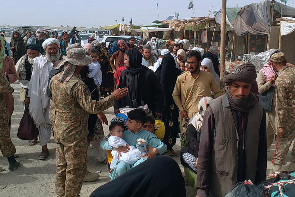 Pakistanische Soldaten überprüfen die Papiere von Menschen, die die Grenze zu Afghanistan an einem Grenzübergang überqueren.