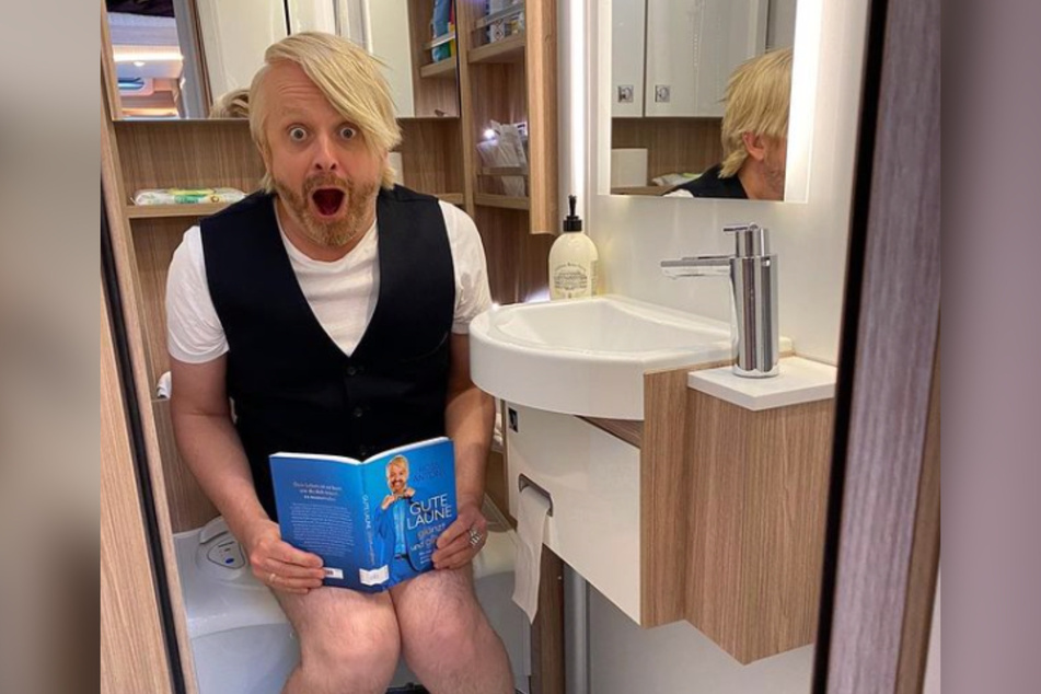 Ross (46) fühlt sich auf der Toilette seines Wohnmobils und mit seinem neuen Buch "Gute Laune glänzt und glitzert" sichtlich wohl.