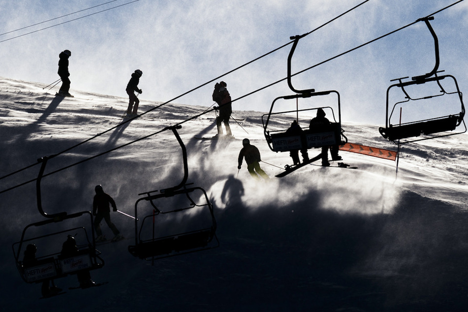 Skifahrer fahren bei starkem Wind eine Piste in Leysin (Schweiz) herunter.