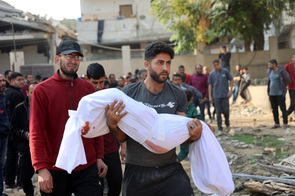 A Palestinian man carries the body of a victim killed in Israeli strikes toward a cemetery in Jabalia in the northern Gaza Strip on November 10, 2024.