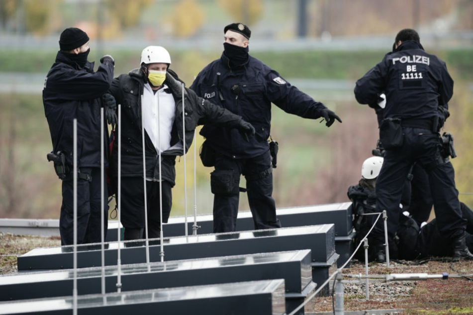 Polizisten begleiten Demonstranten vom Dach vor Terminal 1 am neuen Hauptstadtflughafen BER. Mehrere Gruppen hatten angekündigt, die Eröffnung massiv stören zu wollen.