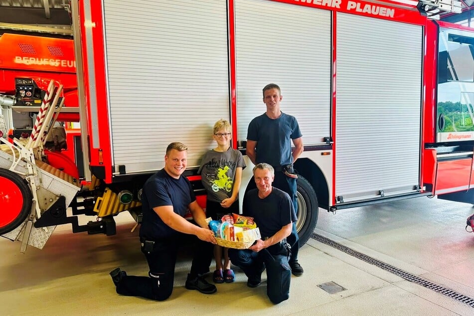 Elias (Mitte) überreichte Nascherein an seine Retter von der Feuerwehr: