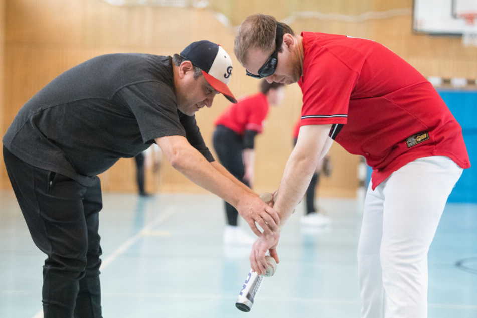 Mahmut, Trainer (l), hilft Josef, Spieler der Blindenbaseball-Mannschaft "Bavarian Bats".