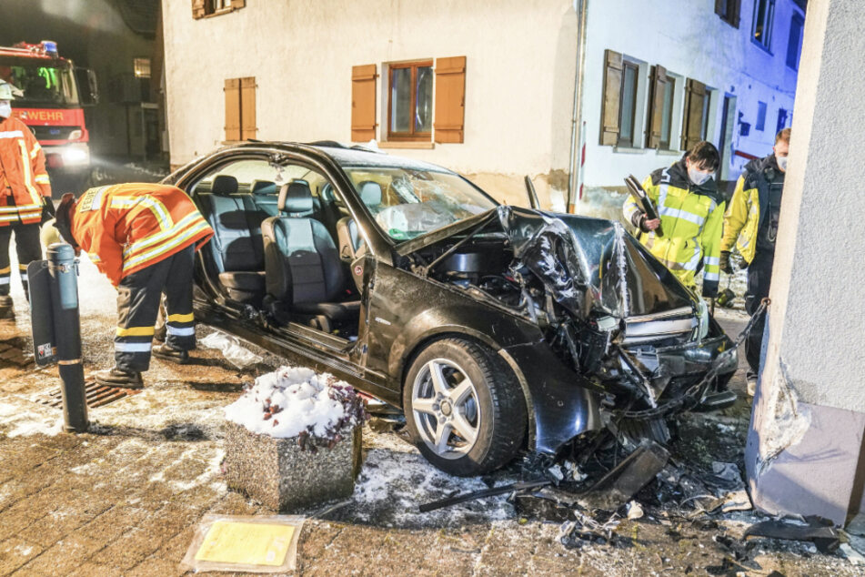 Einsatzkräfte begutachten an der Unfallstelle den völlig demolierten Wagen. Eine 24-Jährige war betrunken in den Hauspfeiler gekracht.