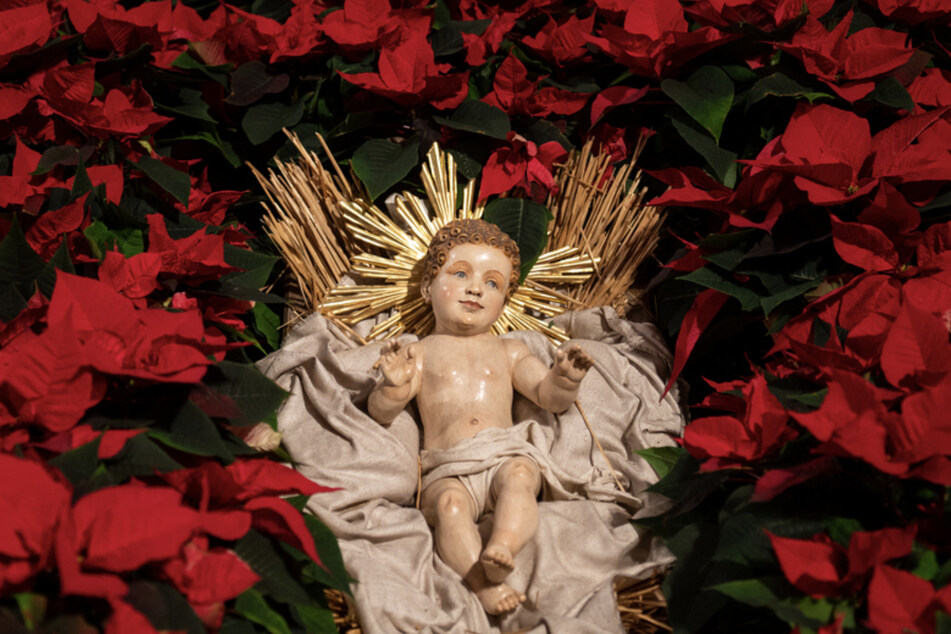 Das Jesuskind liegt im Münchner Liebfrauendom in einer Krippe zwischen Christsternen.