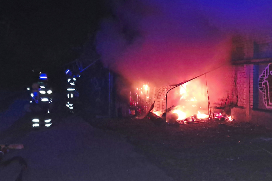 Feuerwehrleute löschen das brennende Material nahe der Lagerhalle in der Heßstraße.