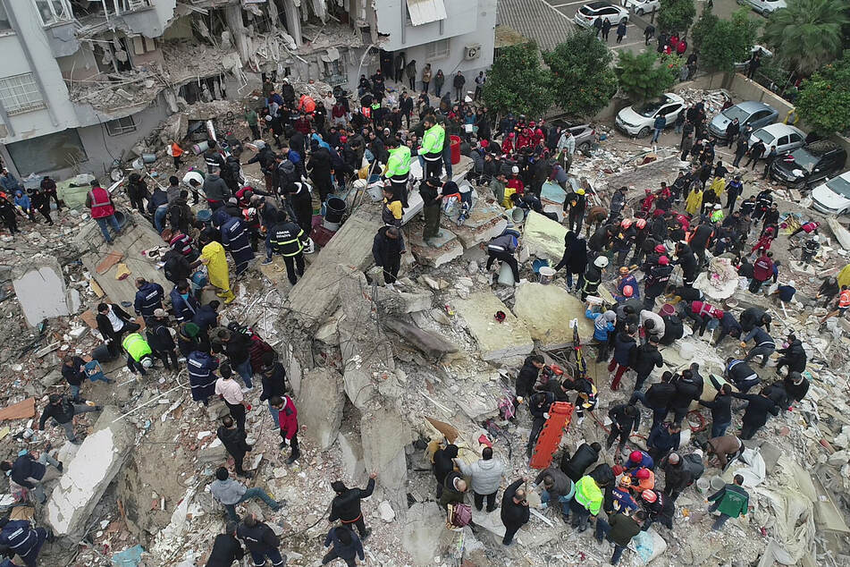 Following a devastating earthquake, people search for survivors among the rubble of a building in Adana, Turkey.