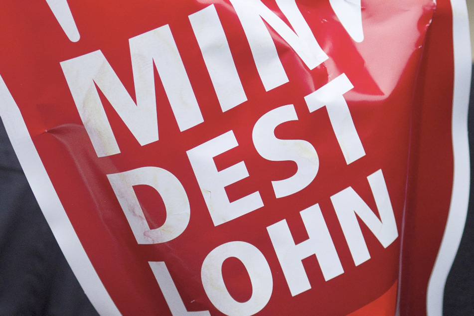 Ein Schild in Form einer roten Hand mit der Aufschrift "Mindestlohn" wird während einer Aktion des Deutschen Gewerkschaftsbundes (DGB) hochgehalten.