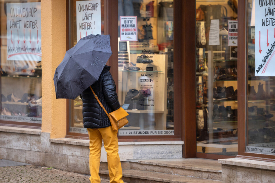 Eine Frau steht vor einem geschlossenen Schuhgeschäft in Gotha. Thüringen kämpft weiterhin mit zu hohen Neuinfektionen.