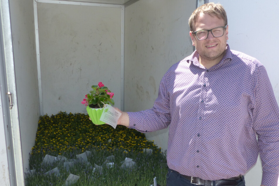 Der Geschäftsführer Schradi (33) steht vor einem Anhänger mit Blumen.