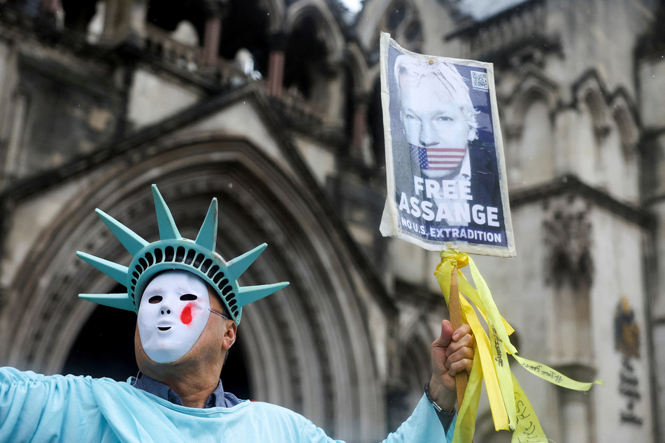 A person wearing a Statue of Liberty costume raises a sign calling for Julian Assange's freedom as supporters of the WikiLeaks founder protest outside the High Court in London.
